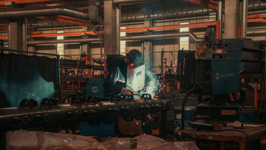 A welder working with metal in a busy factory setting in Konya, Turkey.